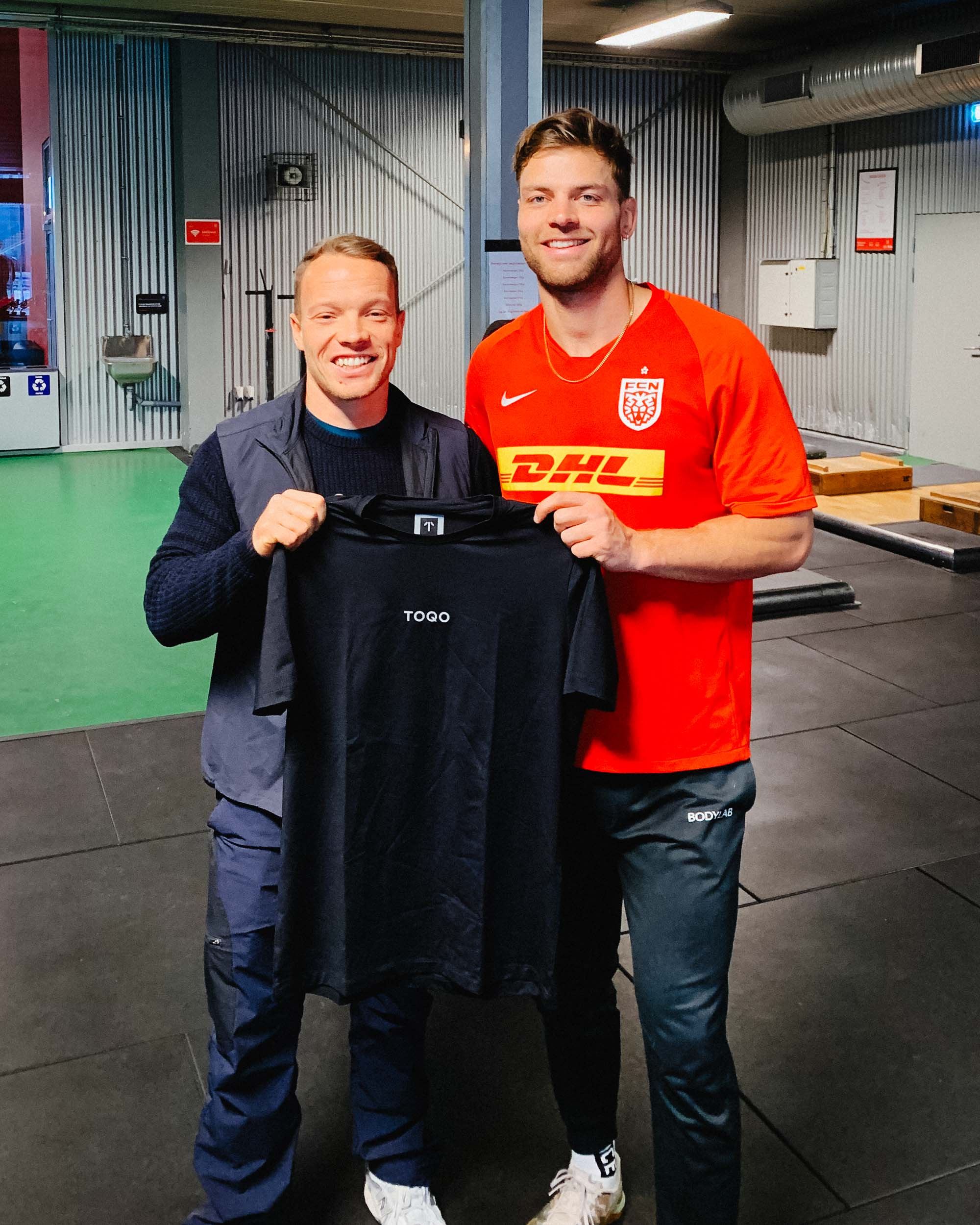 A man holding a TOQO t shirt