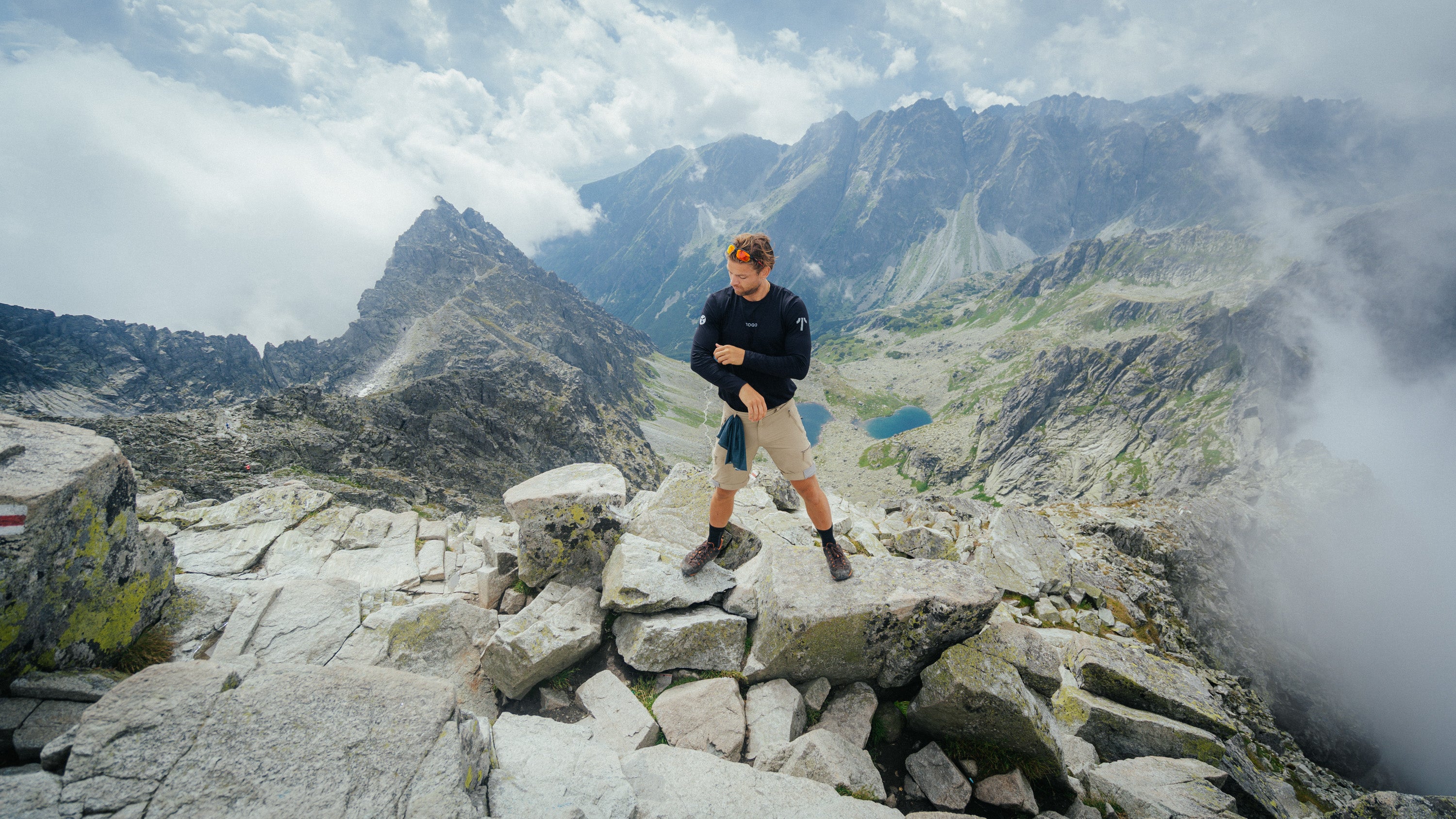 Man with TOQO clothes stands on top of mountain