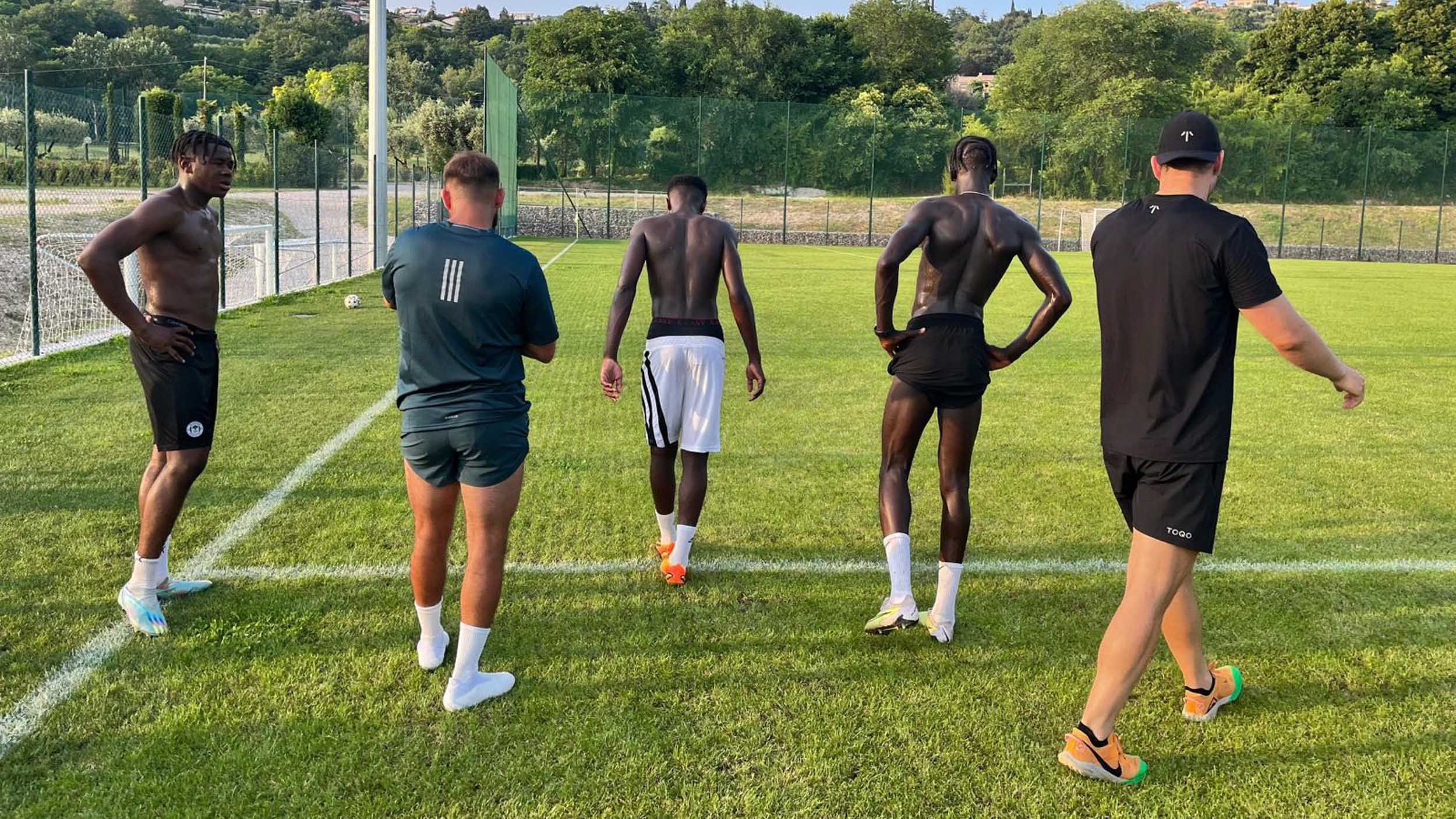 Five men standing on a football field in Italy